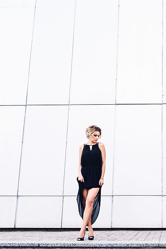 elegant young girl in black dress posing against a gray wall