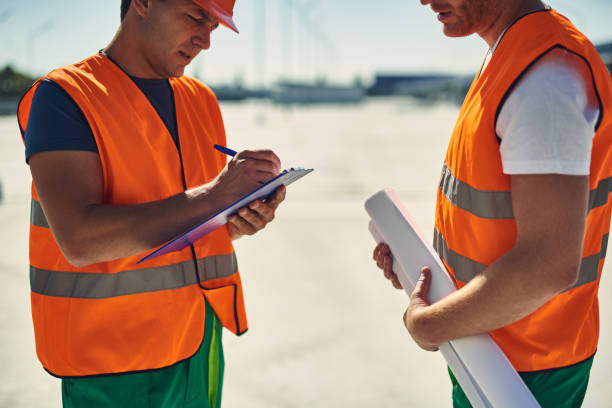 istock Calm builder standing with colleague and making notes on clipboard 1092688436