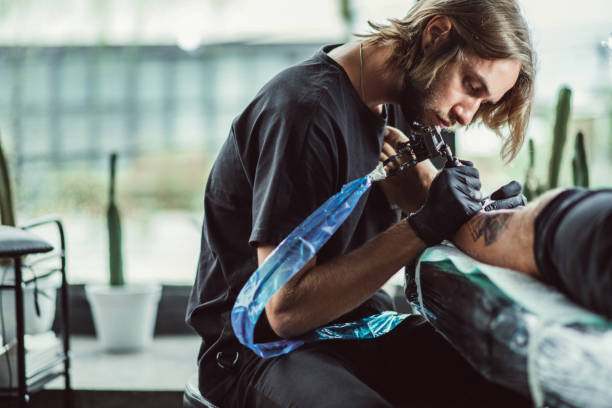 istock Man tattoo artist working in tattoo studio 1092689320