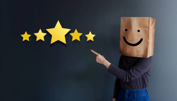 Customer Experience Concept. Woman Covered her head by Paper Bag with Happy Feeling Face and Pointing Hand to Five Star Services Rating Satisfaction. Client's Feedback and Online Review concepto de experiencia de atención al cliente. mujer había cubierta su cabeza por bolsa de papel con cara de sentirse feliz y mano que apunta a los servicios de cinco estrellas de la satisfacción de valorar. retroalimentación y revisión en línea del