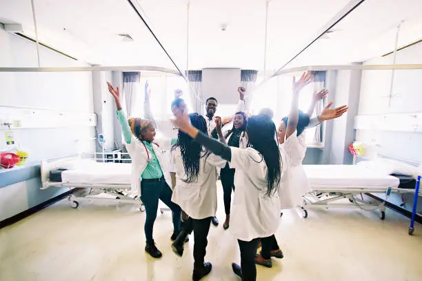 Photo of Group of African medical students celebrating spontaneously together arms raised