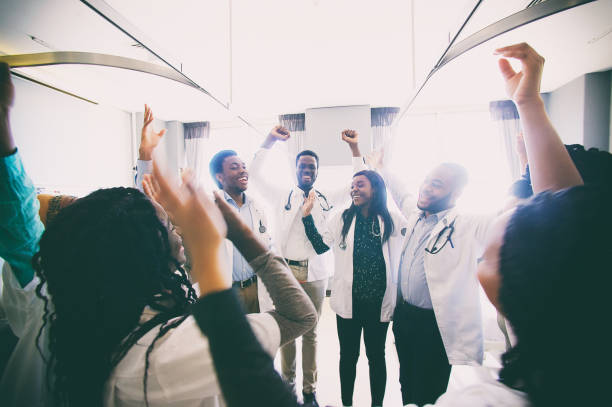gruppo di studenti di medicina africani che festeggiano e ridono spontaneamente insieme - cheering arms raised women university foto e immagini stock