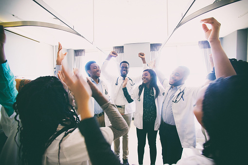 Group of African medical students arms raised cheering celebrating spontaneously as they graduate together in a hospital ward in Cape Town South Africa