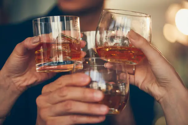 Three people make a toast with whiskey