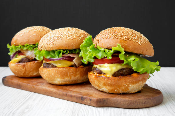 istock Homemade cheeseburgers on rustic wooden board, side view. Closeup. 1092697844