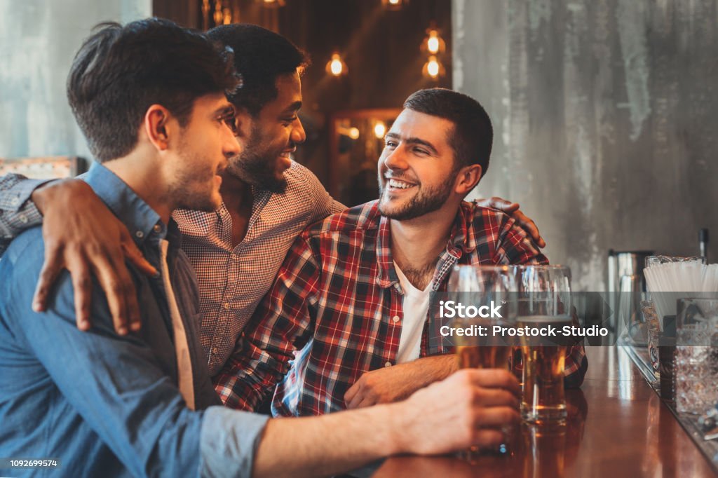 Old friends drinking beer and talking in pub Old friends talking and drinking beer at bar counter in pub Pub Stock Photo