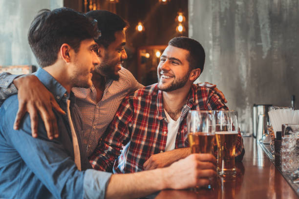 old friends drinking beer and talking in pub - irish culture beer drinking pub imagens e fotografias de stock