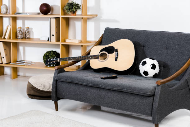 modern living room with acoustic guitar, ball and remote control on sofa