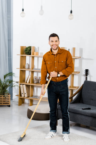 istock cheerful man standing with broom in modern living room 1092702026