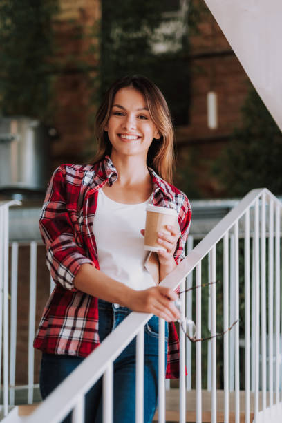 istock Attractive young lady with hot drink posing near handrails 1092705840