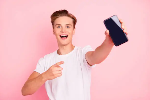 Closeup studio photo portrait of adorable confident dreamy cute handsome delightful optimistic with open mouth boy showing monitor to camera isolated background