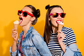 Close up face portrait of two brunette hair dreamy charming lovely cute gorgeous lady in glasses spectacles isolated on yellow vivid background eating sugar tasty yummy appetiser snack