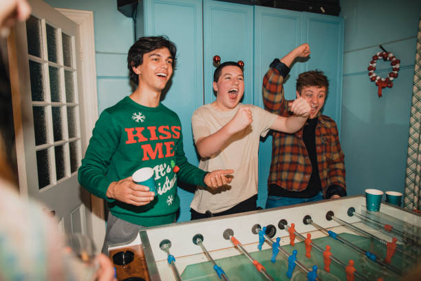 Young Men Playing Foosball at Christmas Three young men are playing as a team in a foosball game at a Christmas party. drunk photos stock pictures, royalty-free photos & images