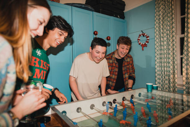 Competitive Christmas Foosball Game Young adults are having a fun but competitive game of foosball at a Christmas house party. drunk photos stock pictures, royalty-free photos & images