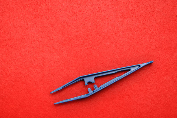 istock A blue plastic tweezers isolated on a red background 1092720652