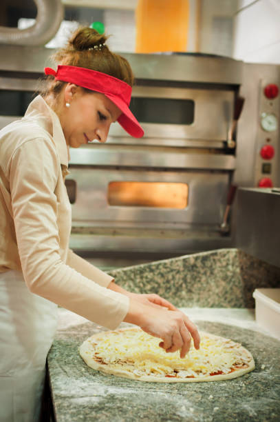 cook spreading tomato sauce and cheese over pizza dough - wheat pasta flour italy imagens e fotografias de stock