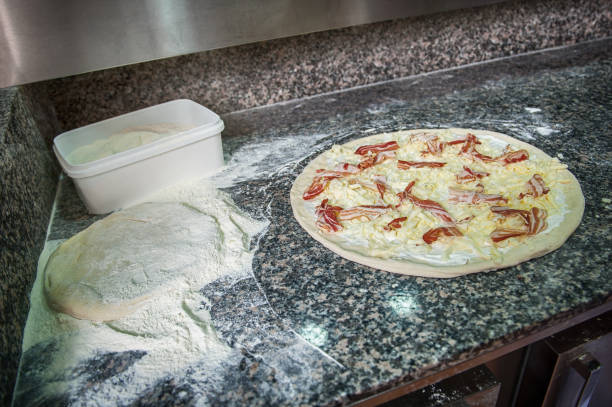 cook spreading cheese and bacon over pizza dough - wheat pasta flour italy imagens e fotografias de stock