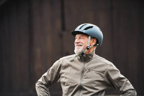 istock Active senior man with bike helmet standing outdoors againts dark background. 1092725232