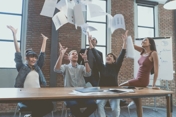 istock Happy Multiethnic Group of young business people throwing documents and looking happy while sitting and standing at their working places in modern office.Celebrating success. winners excited of victory 1092735548