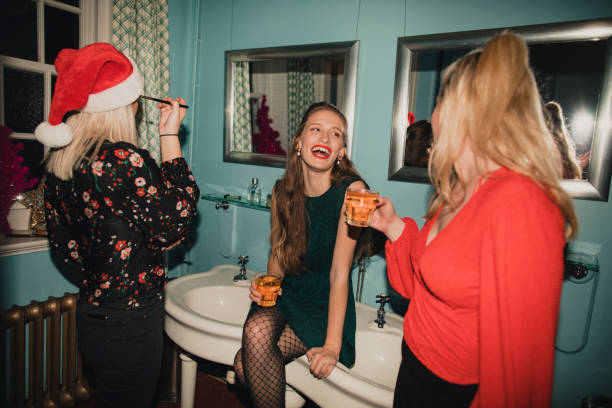 What the Ladies Room Looks Like Three young women are drinking and applying makeup in the bathroom at a house party. cocktail party photos stock pictures, royalty-free photos & images