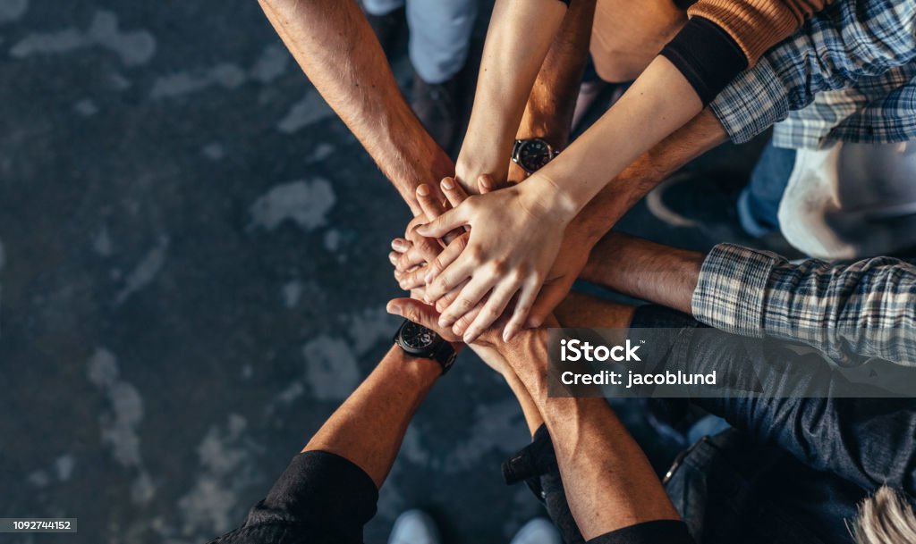 Symbol of teamwork, cooperation and unity Top view of creative professionals putting their hands together as a symbol of teamwork, cooperation and unity. Stack of hands of men and woman. Teamwork Stock Photo