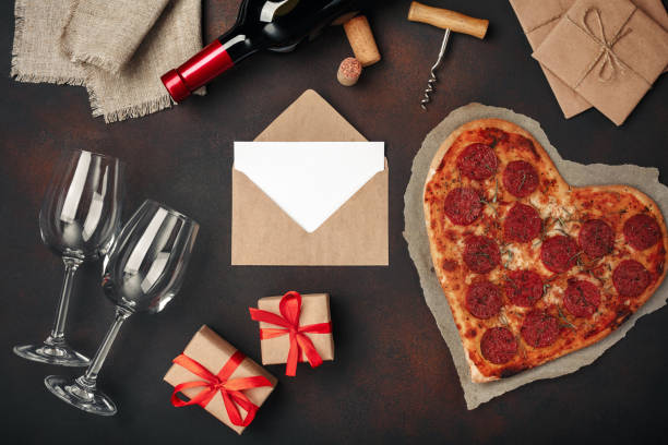 istock Heart shaped pizza with mozzarella, sausagered, wine bottle, two wineglass, gift box on rusty background 1092744538