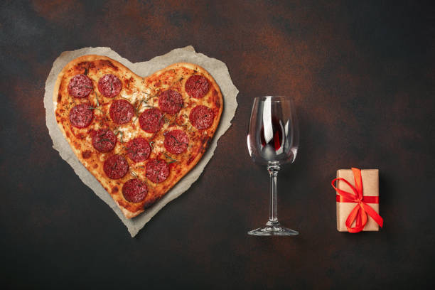 istock Heart shaped pizza with mozzarella, sausagered, wineglass, gift box on rusty background 1092750192