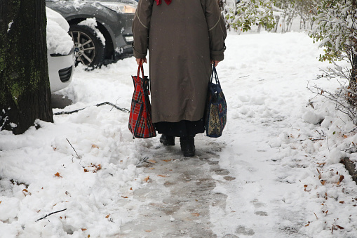 Senior woman walking with shopping bags on snow