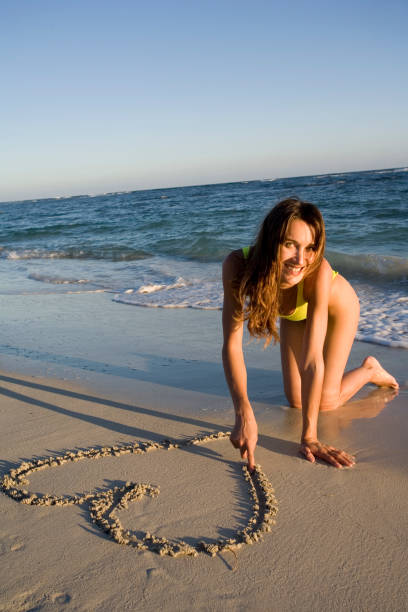 istock woman drawing a heart on the sand 1092757410