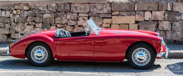 British vintage roadster in front of a stone wall