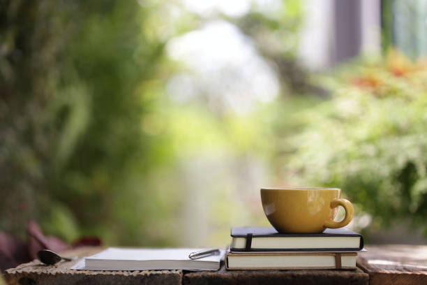 istock Yellow ceramic cup with notebooks at on wooden table 1092761476