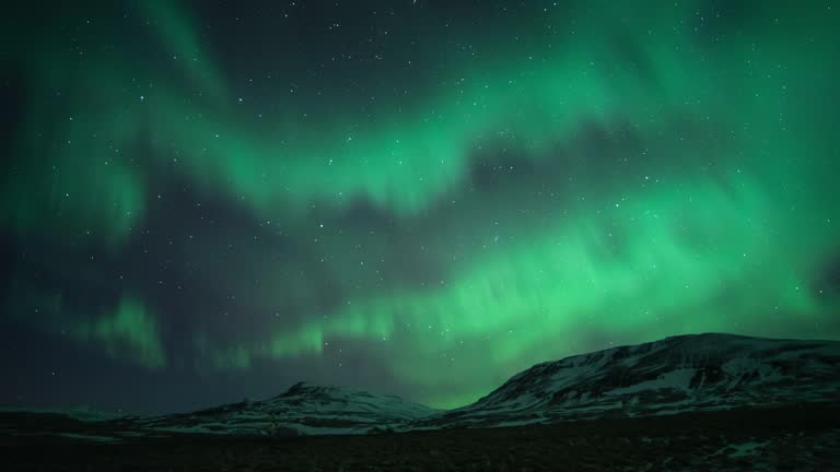 Time lapse of Northern Light or polar light (Aurora Borealis) in the night sky over mountain landscape in winter of Iceland