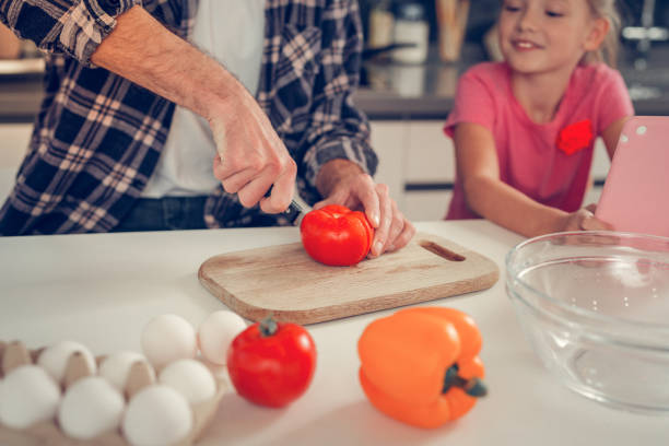 istock Tall bearded dark-haired man cutting a tomato for salad 1092779764