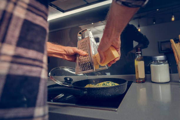 istock Tall man in a checkered shirt grating cheese on the omelet 1092786506