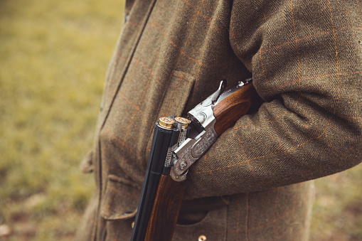 Shotgun open broken over hunter forearm wearing traditional English clothing