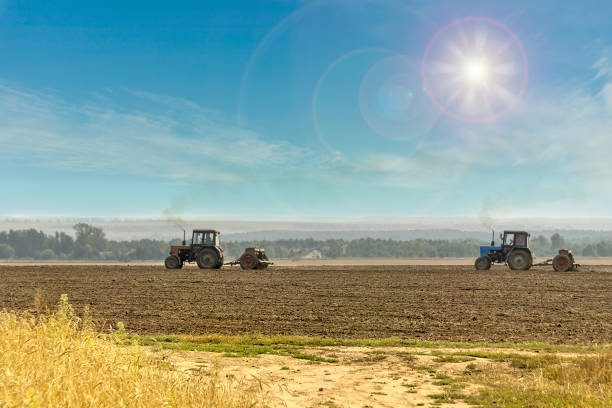 Old tractors with seeders on beautiful sunny agricultural landscape stock photo