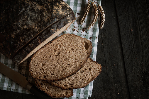 Brown homemade bread on a rustic table. Flat lay image with sliced bread on a kitchen towel