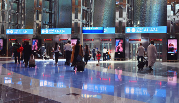 viaggiatori che camminano verso grandi ascensori moderni nella hall dell'aeroporto di dubai - dubai united arab emirates airport indoors foto e immagini stock