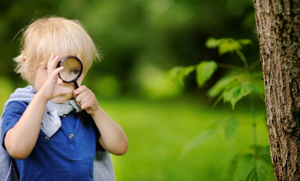 istock Charming kid exploring nature with magnifying glass 1092811514