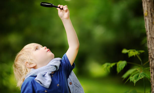 istock Charming kid exploring nature with magnifying glass 1092811522