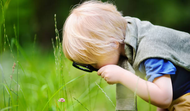 istock Charming kid exploring nature with magnifying glass 1092811536