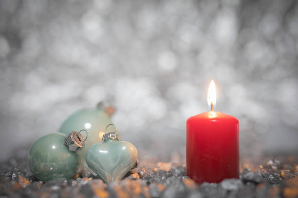 Bright yellow flame of a Christmas candle on the background of red Christmas tinsel.