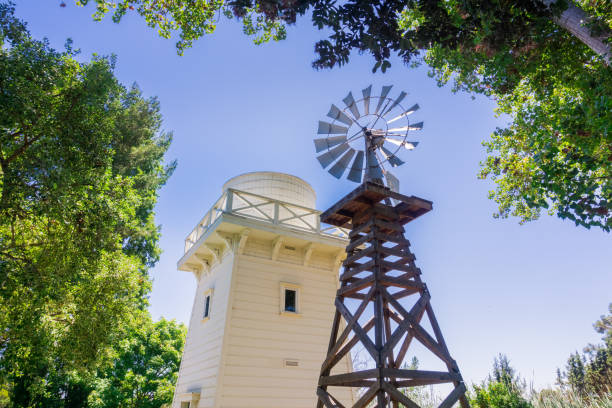 old wind turbine and wooden water tower, rengstorff house, shoreline lake and park, mountain view, california - water pumping windmill imagens e fotografias de stock