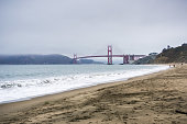 People walking on a sandy beach close to Golden Gate Bridge, San Francisco, California