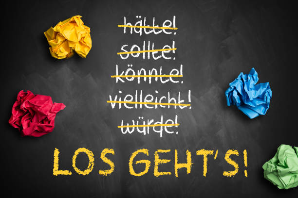 chalkboard with crumpled paper and stroked words like could and should and "Let's go" in German stock photo