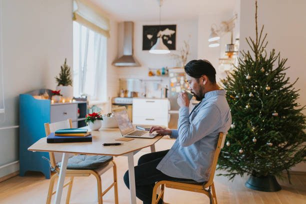 Single Asian man does Christmas online shopping and drinks coffee