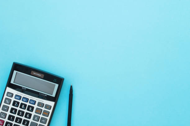 Calculator and pen on a blue background. Calculator and pen on a blue background. Top view. operating budget stock pictures, royalty-free photos & images