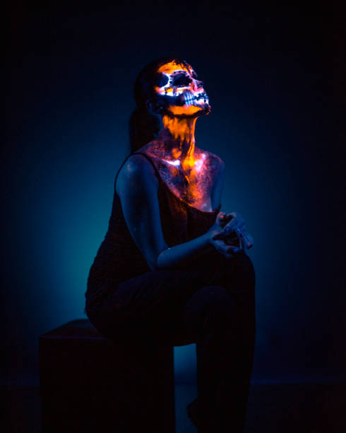 Girl's Face painted in fluorescent UV colors and looks like Neon Glowing Skull