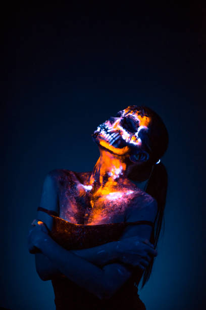 Girl's Face painted in fluorescent UV colors and looks like Neon Glowing Skull
