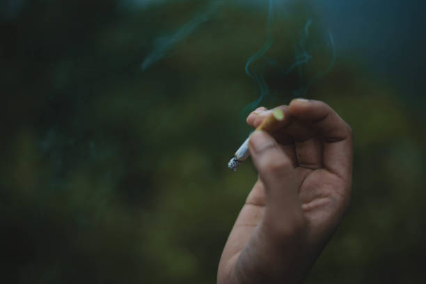 istock Burning Cigarette and Smoke in a hand with Green Background 1093072558
